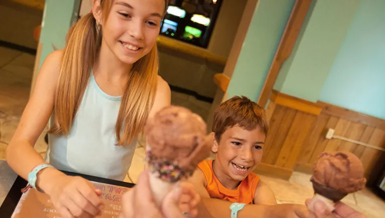 Two kids reach out to grab ice cream cones at Bear Claw Cafe at Great Wolf Lodge indoor water park and resort..