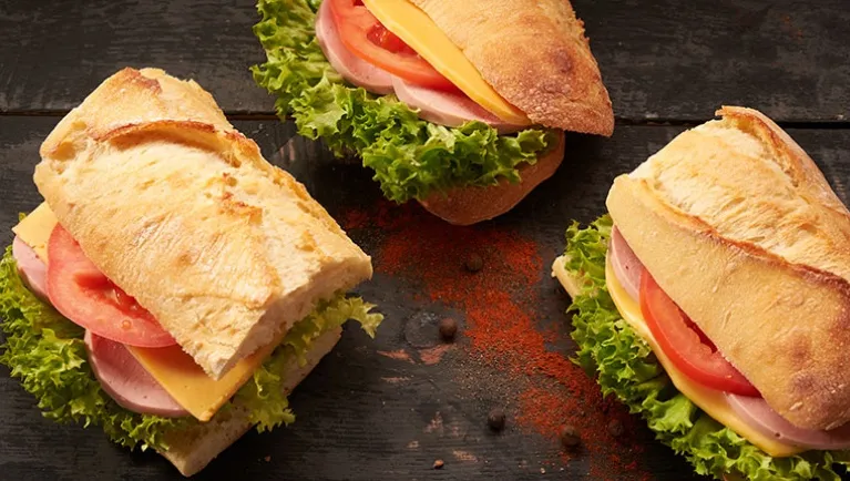 Three sandwiches filled with lettuce, tomato, cheese and turkey