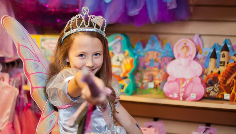 A girl points at the camera while shopping at MagiQuest Marketplace at Great Wolf Lodge indoor water park and resort.