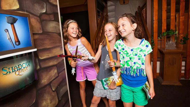 Three girls smile as they play ShadowQuest at Great Wolf Lodge indoor water park and resort.