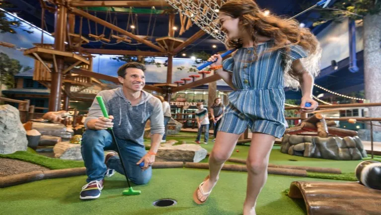 A couple enjoys a round of mini golf at Great Wolf Lodge indoor water park and resort.
