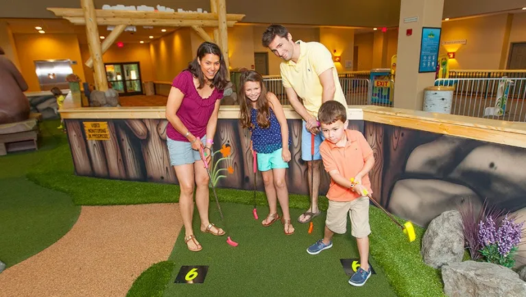 A family of four play Howl at the Moon Mini Golf at Great Wolf Lodge indoor water park and resort.