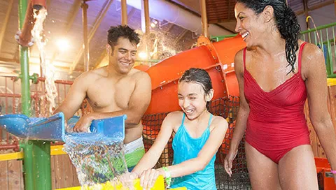 A family plays in the Talking Stick Treehouse water attraction at Great Wolf Lodge indoor water parks and resorts.