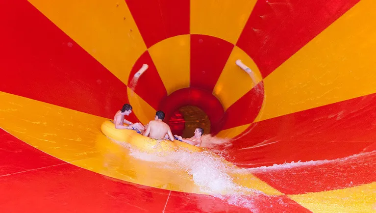 A family of four ride a tube down the Howlin' Tornado water slide