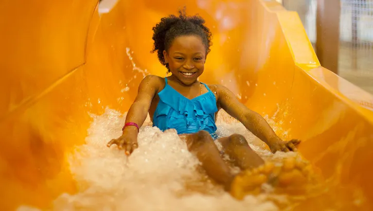 A girl smiles as she rides a water slide