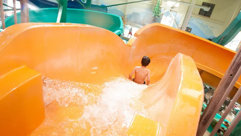 A boy slides away down a water slide