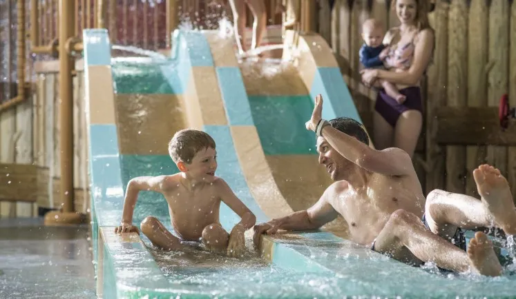 A father and son comes down from a water slide at a Great Wolf Lodge indoor water park.